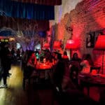 Ambiente de bar com iluminação quente, decoração moderna e clientes desfrutando de drinks e conversa.